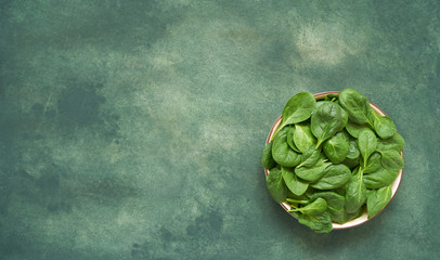 Fresh spinach leaves on white plate. Healthy vegan food. Top view, copy space