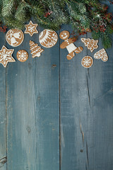 Christmas gingerbread on a blue wooden table decorated with branches of spruce. A Symbol Of Christmas. Festive food. The gingerbread man. Table decoration for the holiday. Christmas card. Empty space