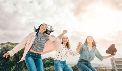 Happy Asian girls jumping outdoor - Young women friends having fun during university break -...
