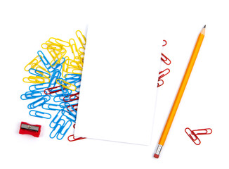 Top view of a white sheet of paper lying on paper clips. Near pencil, sharpener. copy space for text