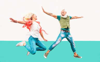 Happy crazy couple jumping together outdoor - Mature trendy people having fun celebrating and dancing outside - Concept of happiness, freedom, carefree, love and relationship