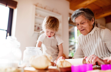 Obraz na płótnie Canvas Senior grandmother with small toddler boy making cakes at home.