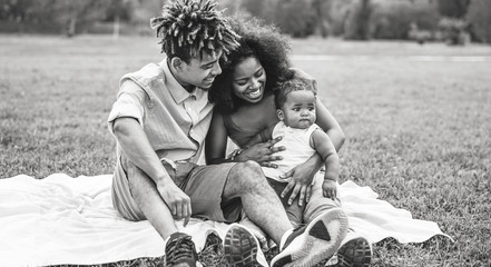 Happy African family having fun during the weekend in public park - Mother and father playing with their daughter outdoor - Love, parenthood and happiness concept - Black and white edited