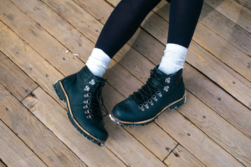 Unrecognizable young woman's feet in white high socks and black boots. Girl walking in the city.
