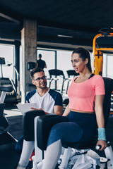 Young fit and attractive woman working out in modern gym together with her personal fitness instructor or coach.