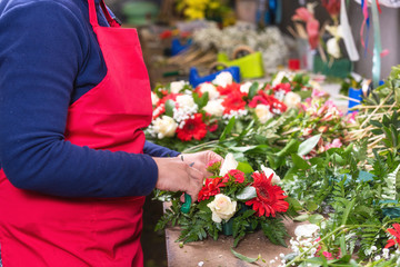 Close up of female florist creating beautiful bouquet at flower shop .