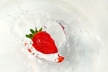 red strawberries falling into the water with splashes
