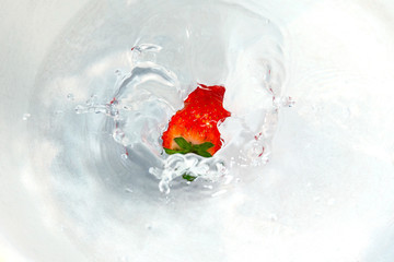 red strawberries falling into the water with splashes