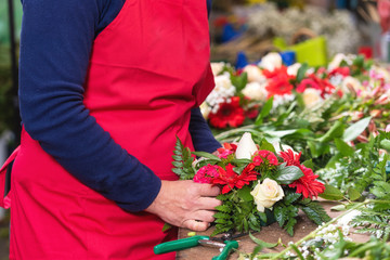 Close up of female florist creating beautiful bouquet at flower shop .