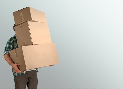 Delivery man carrying stacked boxes in front of face against  background