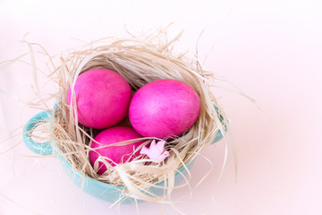 3 pink eggs in a nest on a beige background, Easter, doves, plate, top view