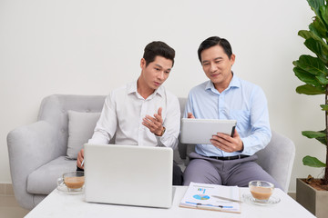 Obraz premium Handsome businessman smiling while working with a laptop at home