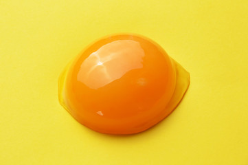 Raw egg yolk on the yellow background
