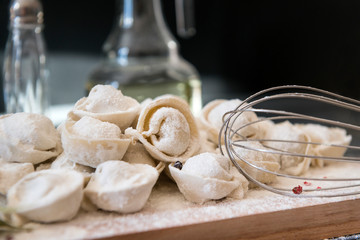 raw dumplings in flour on cutting Board, whisk,