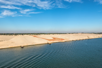 The western side of Suez Canal. Foreground - construction site. In the background - railway, buildings and palm trees. View from the water, Suez Canal, Egypt.