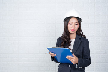 Woman of Engineering holding a hat, separate the white brick wall Made gestures with sign language.