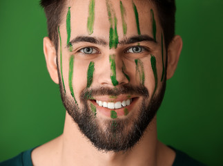 Portrait of handsome man with paint on his face against color background