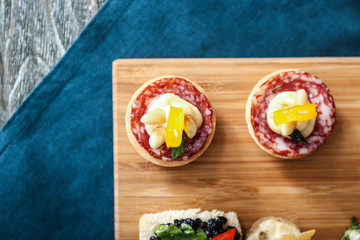 Tasty canapes on wooden board