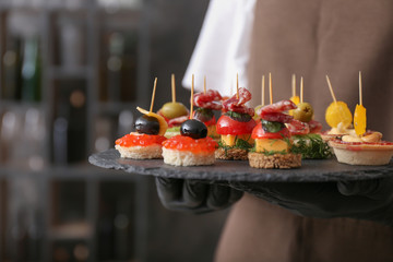 Chef holding slate plate with tasty canapes, closeup