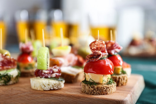 Tasty canapes on wooden board, closeup