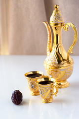 Still life with traditional golden arabic coffee set with dallah and cup. White background. Ramadan concept.