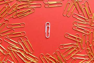 White paper clip among golden ones on color background. Concept of uniqueness