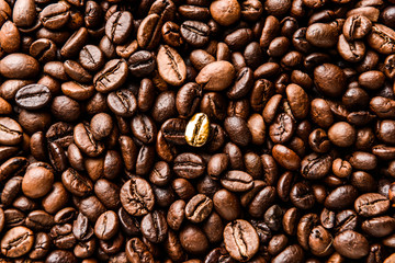 One golden coffee bean among brown ones, closeup. Concept of uniqueness