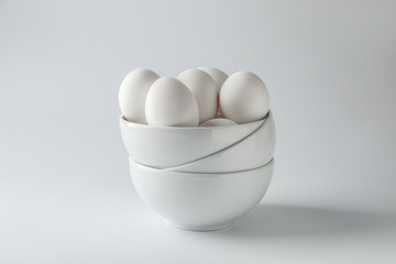 Bowls with tasty raw eggs on white background