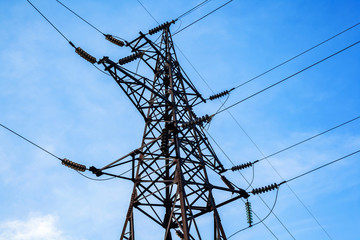 High voltage electricity pylon and transmission power line on the blue sky and white clouds on the background. Parts of electrical equipment and high voltage power line insulators.