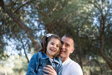 Handsome father and his pretty daughter pose in the park