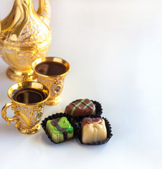 Still life with traditional golden arabic coffee set with dallah, cup and chocolate candy. White...
