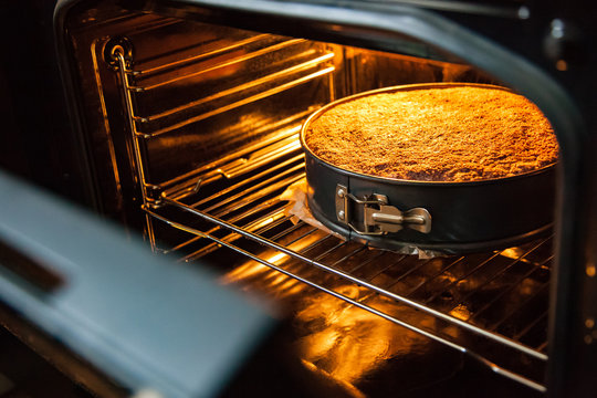 Homemade cake is prepared and baked in a special form for baking in an electric oven in the kitchen. View of the finished cake with the oven door open.