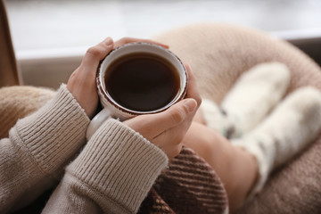 Young woman drinking hot tea at home, closeup