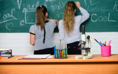 Girls classmates study chemistry. Microscope and test tubes on table. Chemical reactions. Make studying chemistry interesting. Pupil at chalkboard on chemistry lesson. Educational experiment concept