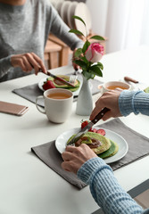 Women eating tasty green pancakes at table