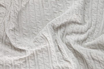 white knitted blanket. lying on white wooden floor in soft folds. in the centre of the empty place of inscription, text.