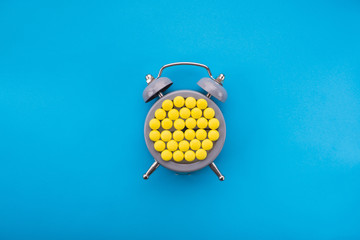 Yellow pills with time clock on a blue background