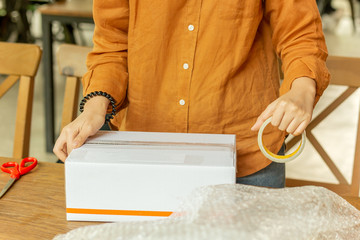 Startup small business woman owner packing cardboard box at workplace.