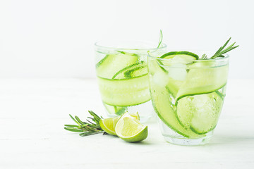 Drink from fresh cucumber juicy lime and a sprig of rosemary in glass glasses on a white background. Selective focus.