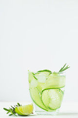 Drink from fresh cucumber juicy lime and a sprig of rosemary in glass goblet white background. Summer refreshing detox.