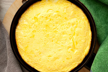 Omelet in a pan closeup. View from above. Omelette of chicken eggs in the pan in the kitchen among the towels. Protein in an appetizing omelet.