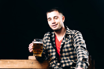 a man with a glass of beer sitting on a bench on a black background