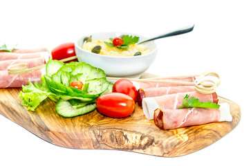 Pieces of Italian prosciutto on a wooden cutting board