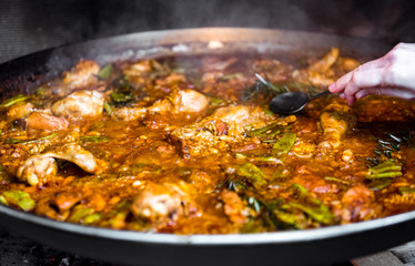 Cooking and making a traditional Spanish Paella over open fire.