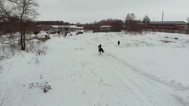 A young woman riding a horse on a snowy field in a village