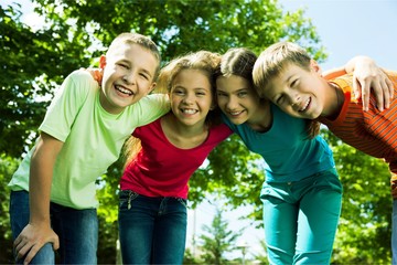 Fototapeta premium Happy smiling diverse kids hugging in park
