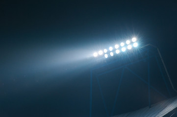 Stadium lights against dark night sky background. Soccer match lights.