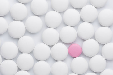 One pink pill between many white pills