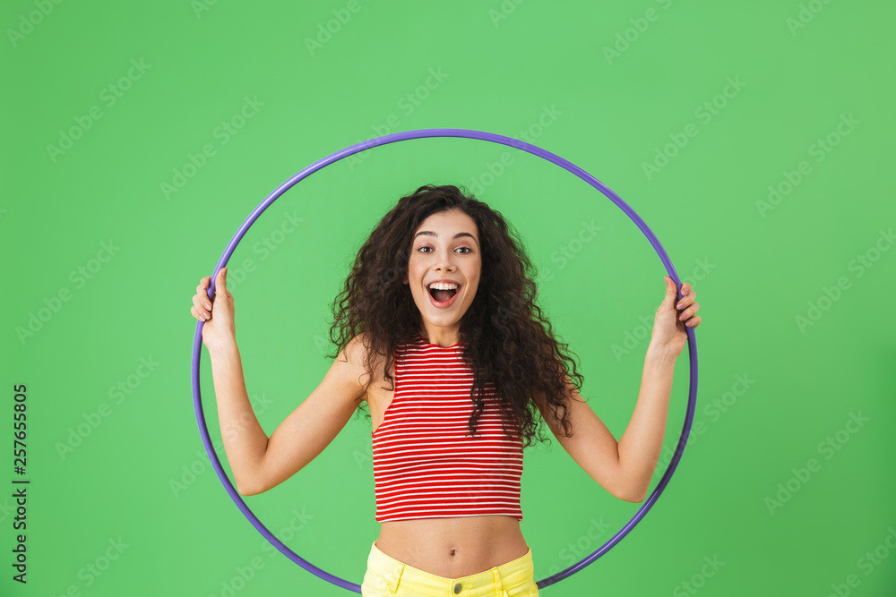 Wall mural photo of energetic woman 20s wearing summer clothes doing exercises with hula hoop during gymnastics