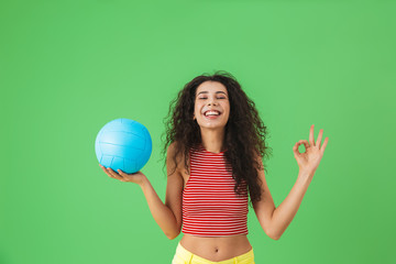 Image of joyful woman 20s wearing summer clothes smiling and holding volley ball